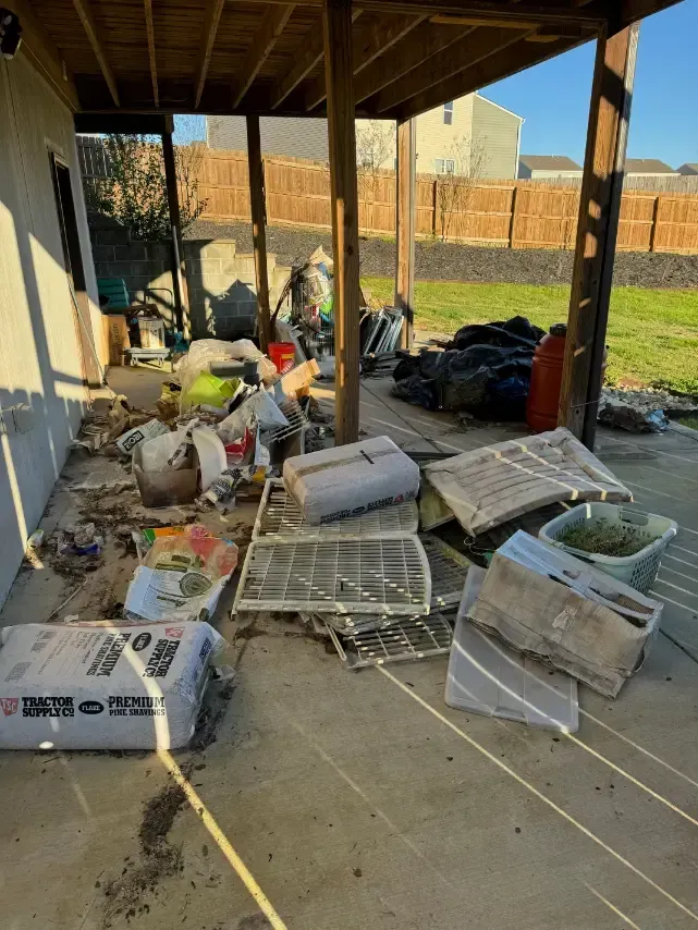 There is a lot of trash on the ground in the backyard of a house.