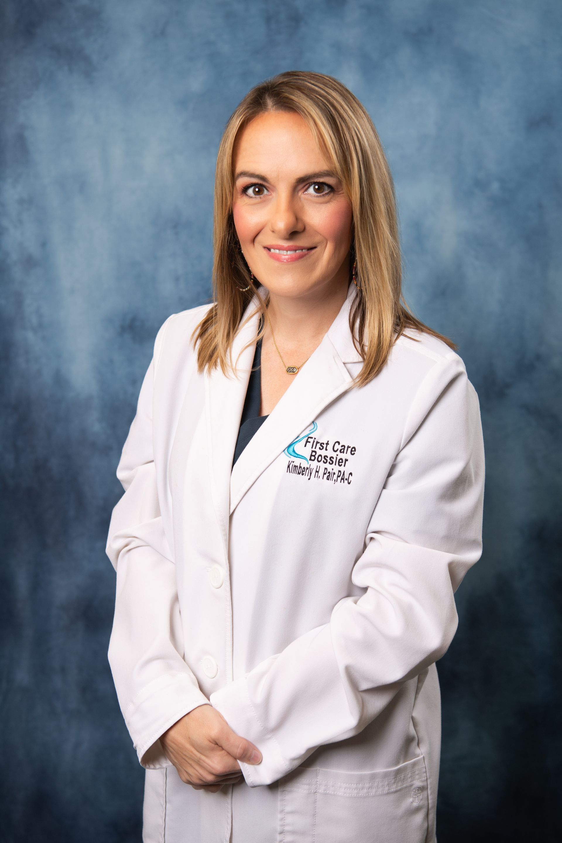 A woman in a white lab coat is smiling for the camera.