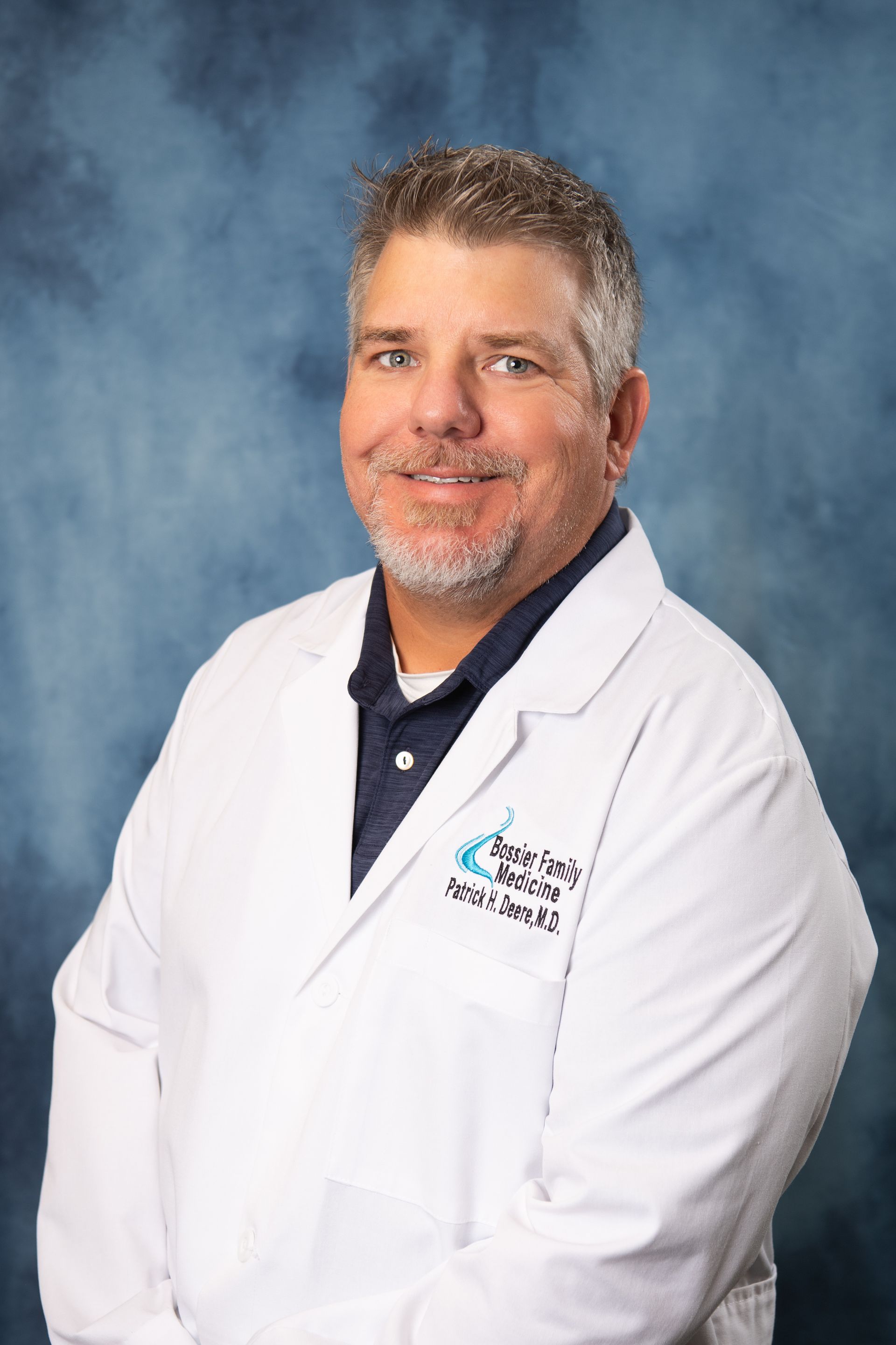 A man in a white lab coat is smiling for the camera.