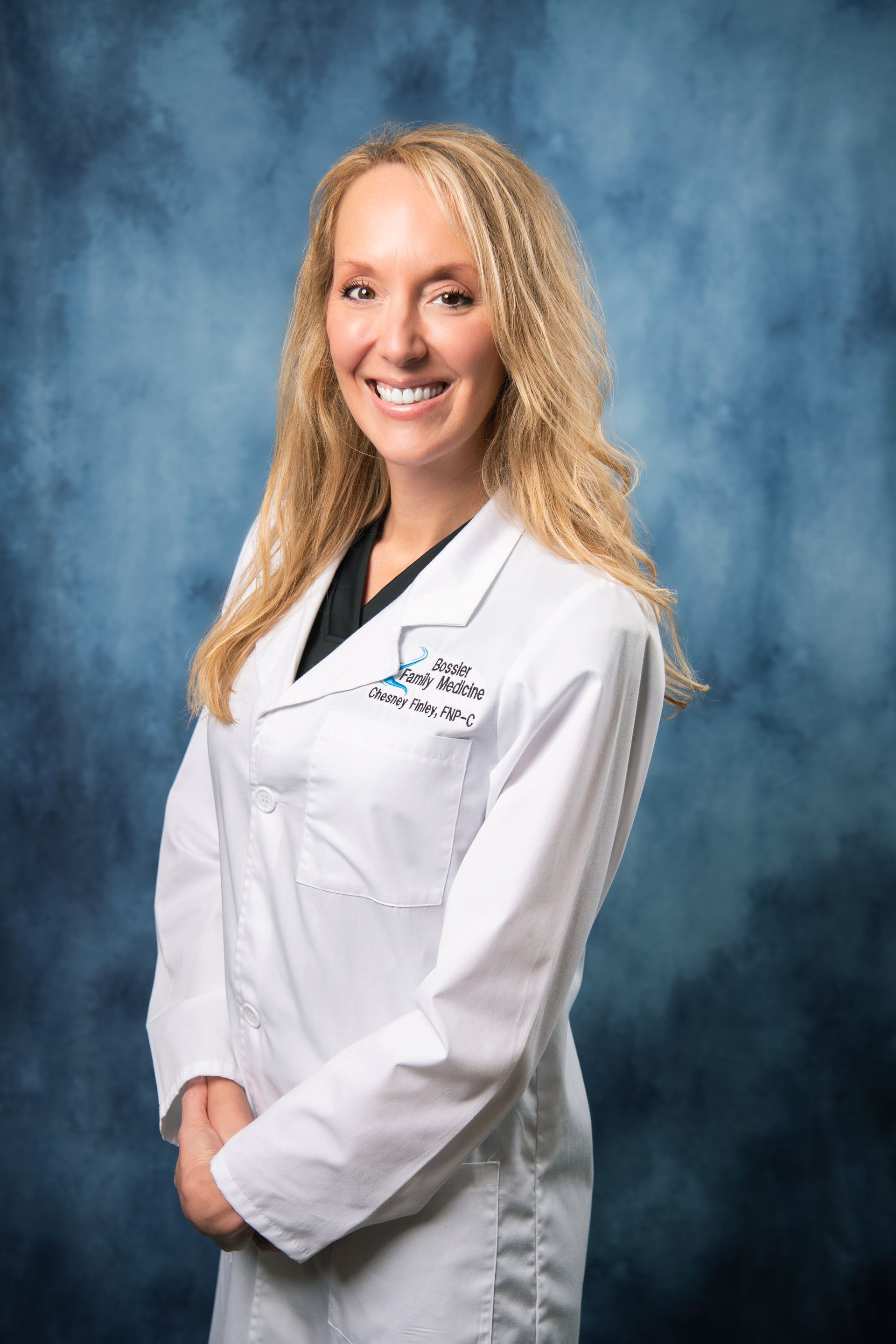 A woman in a white lab coat is smiling for the camera.