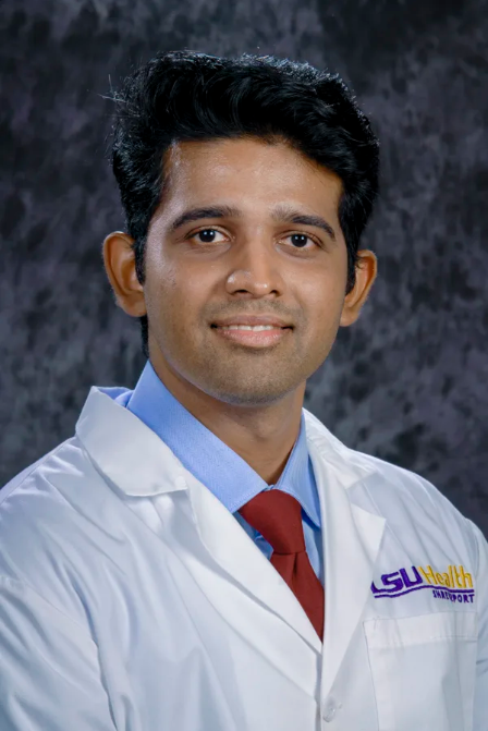A man wearing a white lab coat and a purple tie