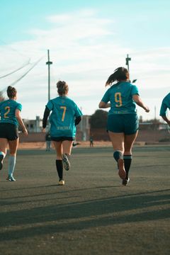 A group of female soccer players are running on a field.