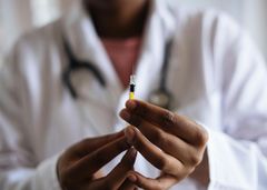 A doctor is holding a syringe in his hands.