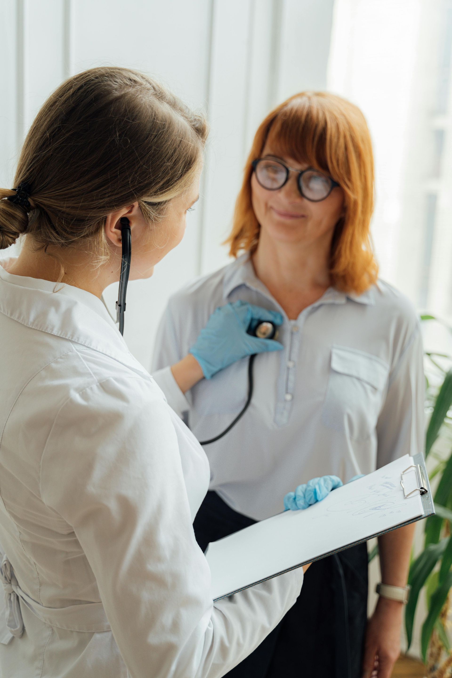 A doctor is listening to a patient 's heartbeat with a stethoscope.