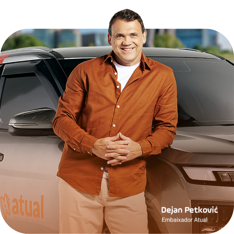 Homem sorridente com camisa laranja em pé na frente de um carro com o logotipo da Mutual e a inscrição 