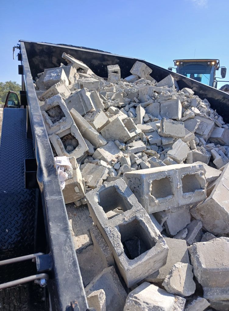 Dump truck filled with broken concrete blocks under a clear sky.