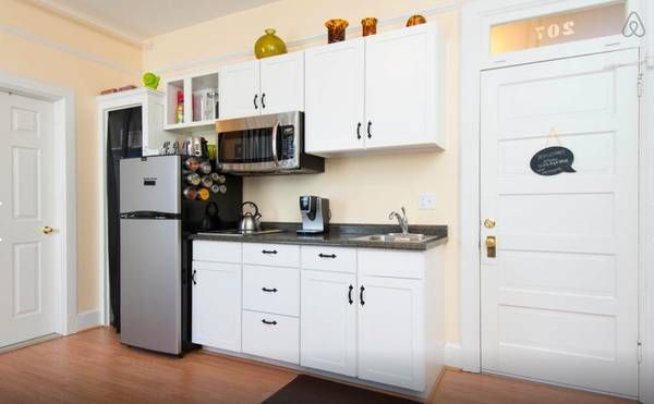 A kitchen with white cabinets , a refrigerator , a microwave , and a sink.