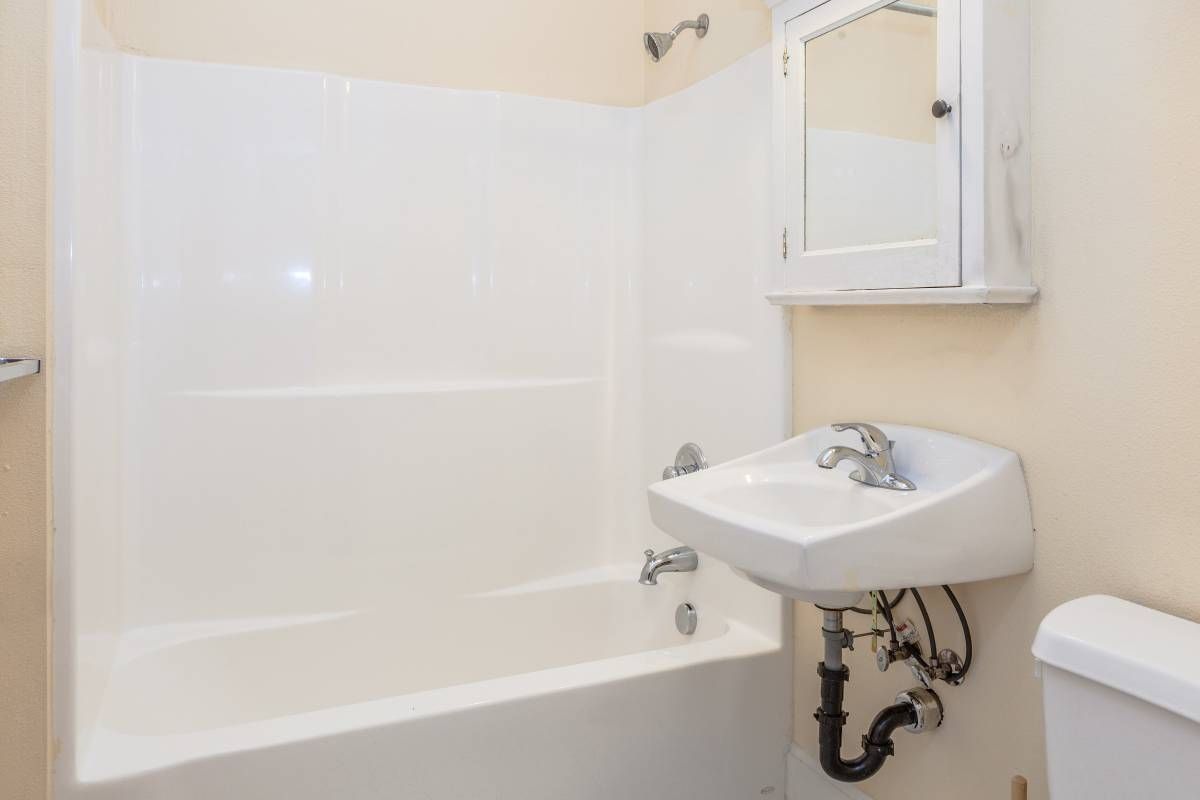 A bathroom with a sink , bathtub , mirror and toilet.