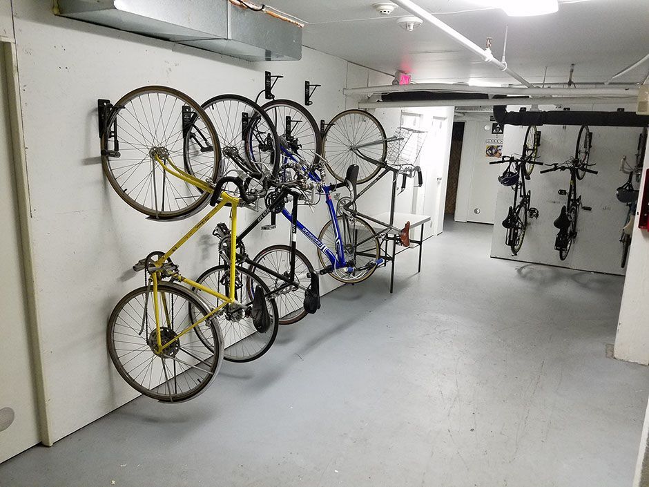 A row of bicycles are hanging on a wall in a garage.