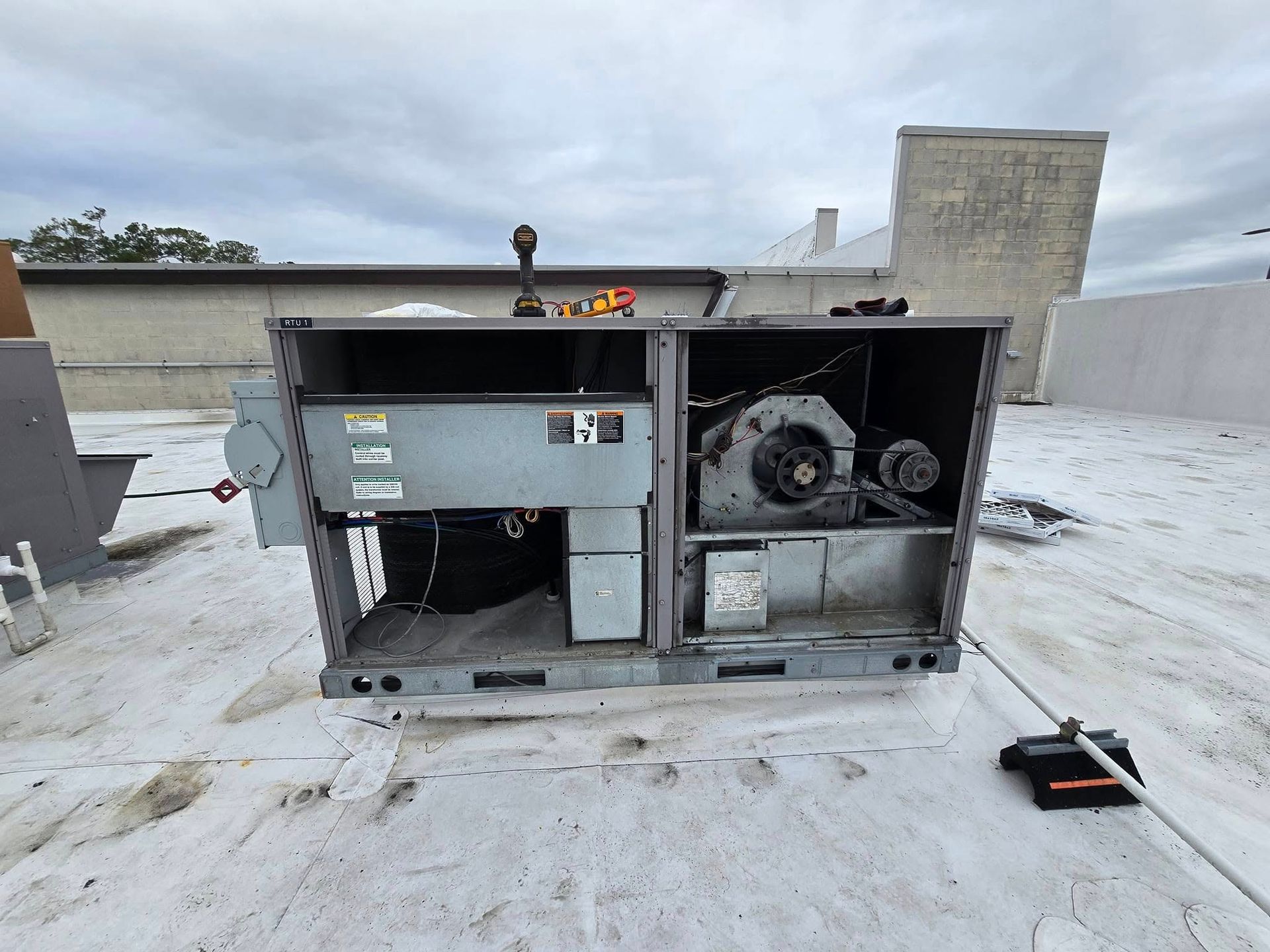 An air conditioner is sitting on top of a white roof.