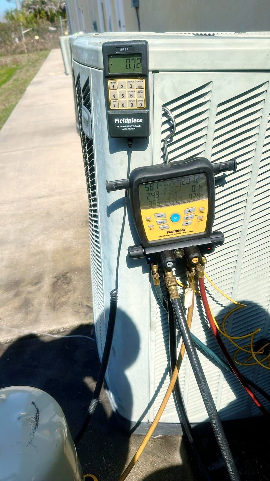A digital thermometer is attached to the side of an air conditioner.