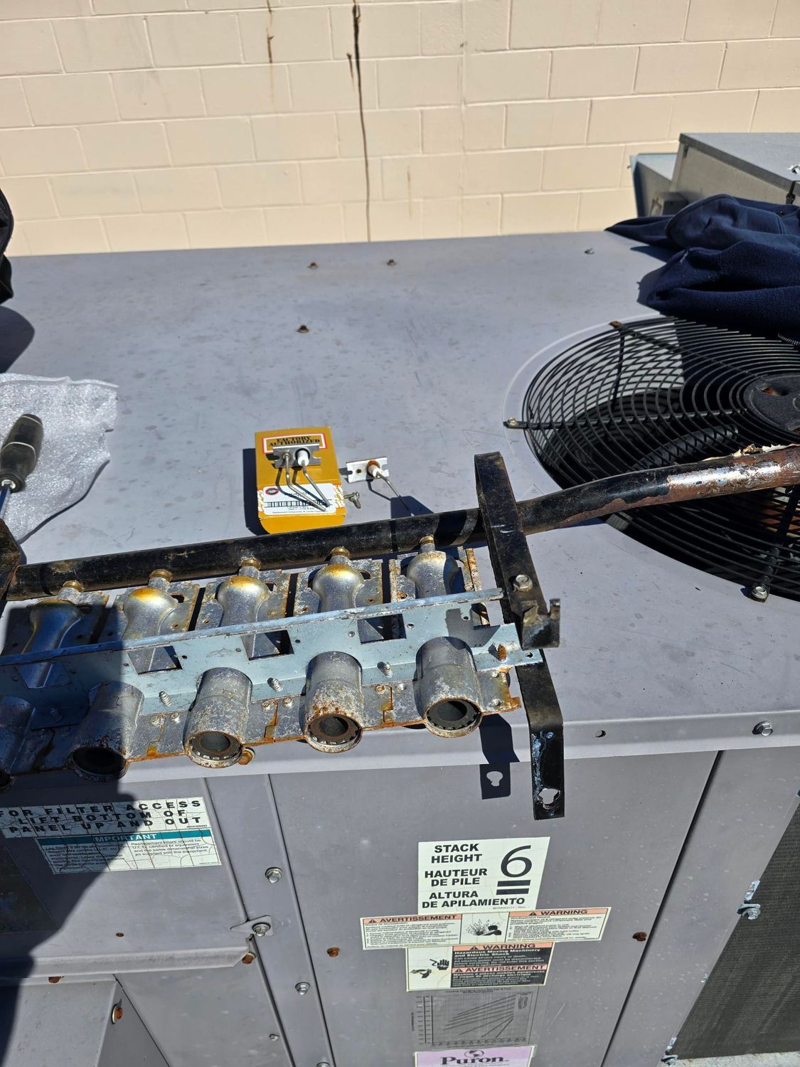 A person is working on an air conditioner with a thermometer on top of it.