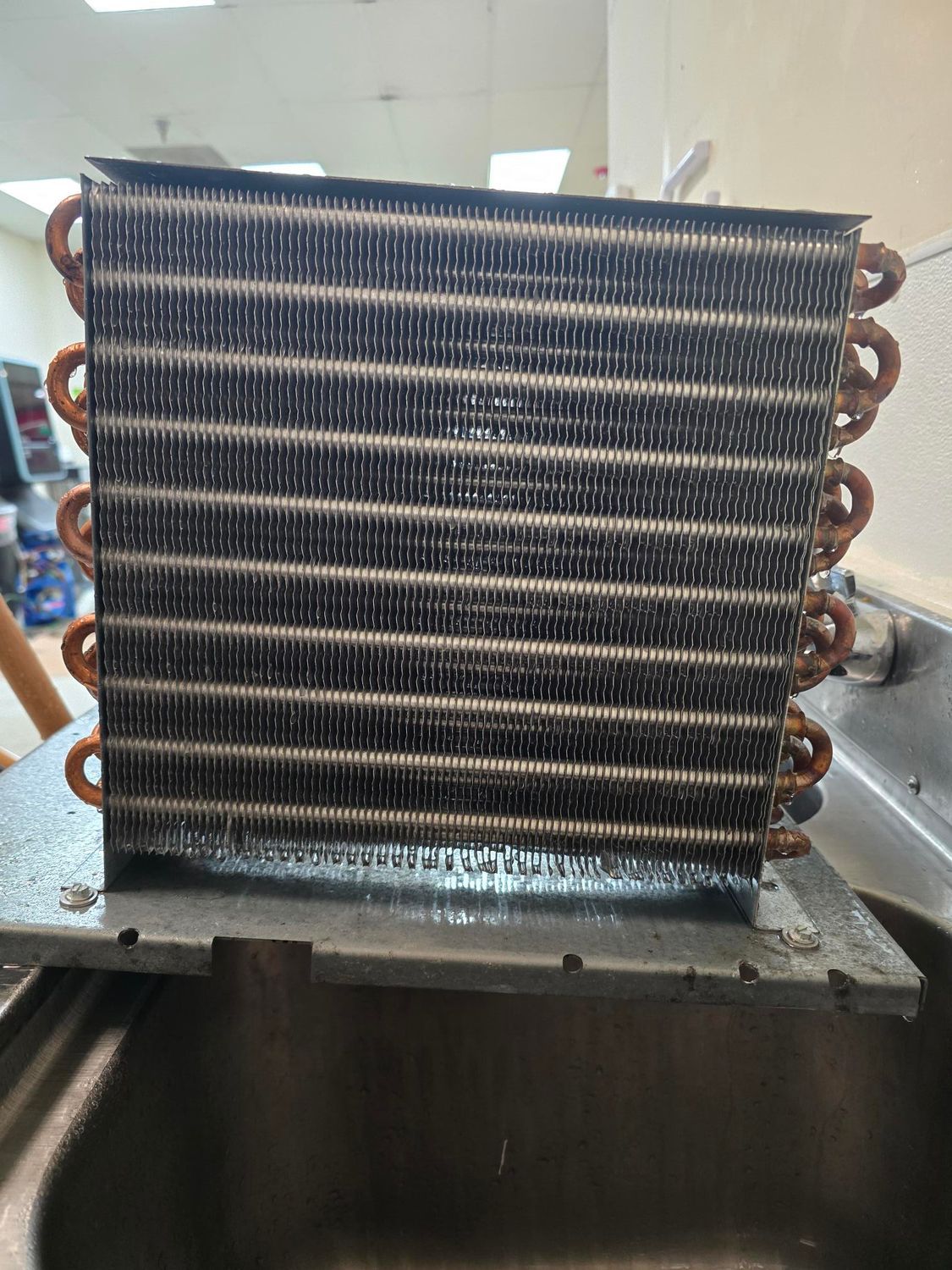 A refrigerator evaporator is sitting on top of a sink.