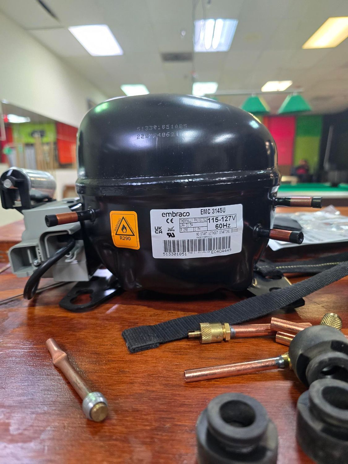 A black compressor is sitting on top of a wooden table.