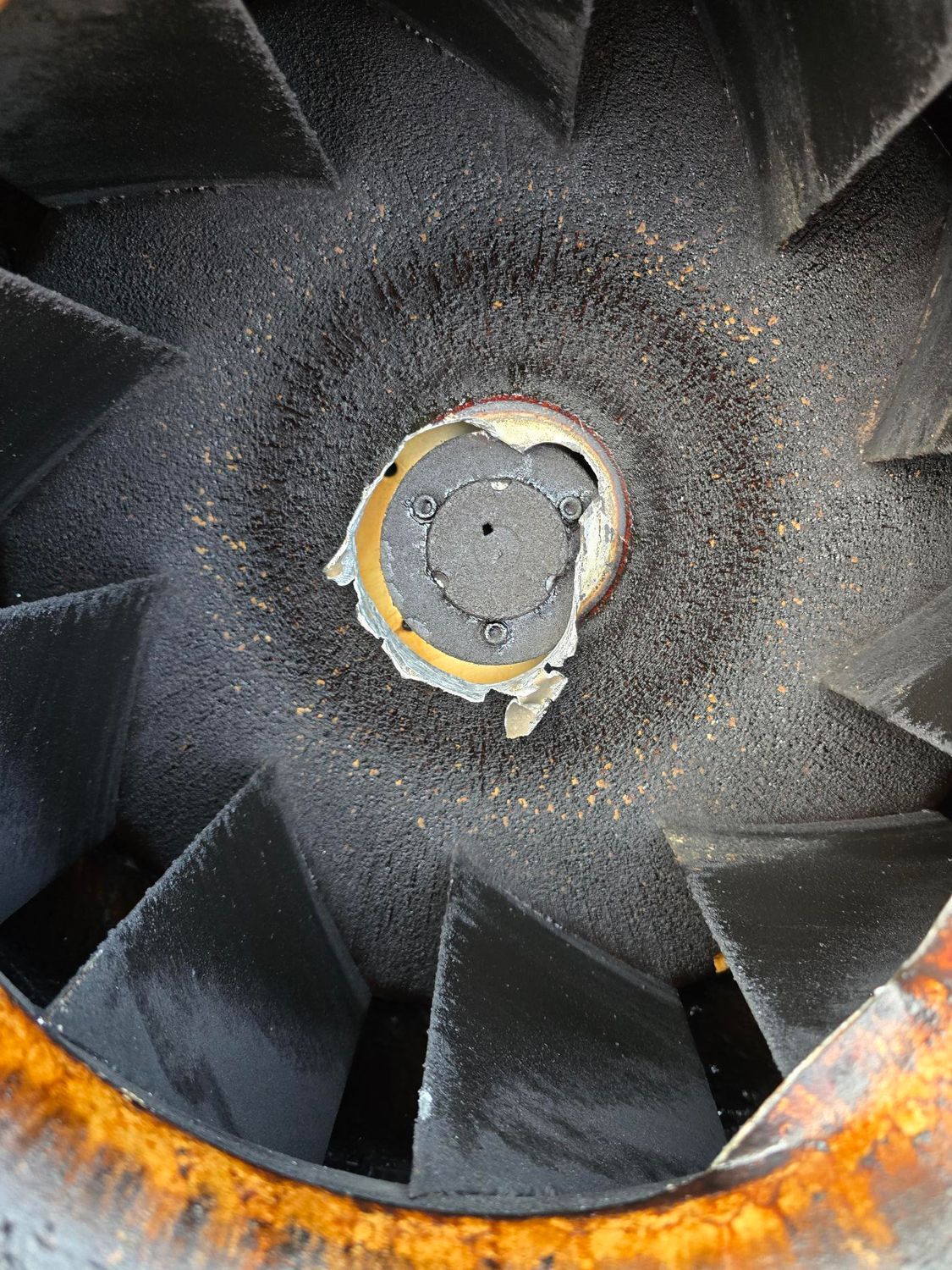 A close up of a rusty fan with a hole in the middle.