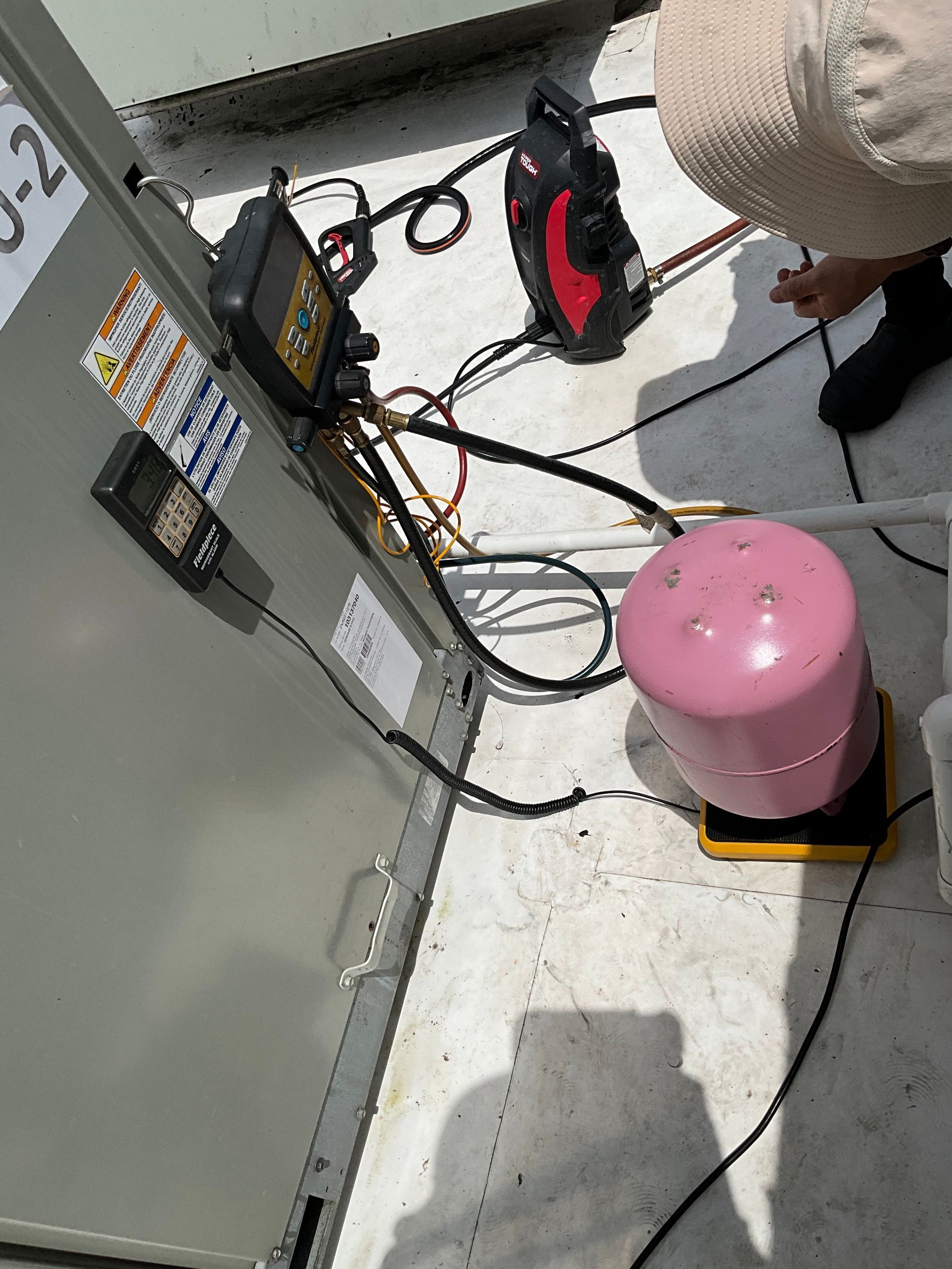 A person is working on an air conditioner with the number j-2 on it