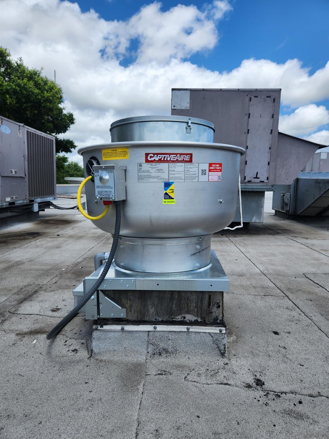 A large metal fan is sitting on top of a concrete roof.