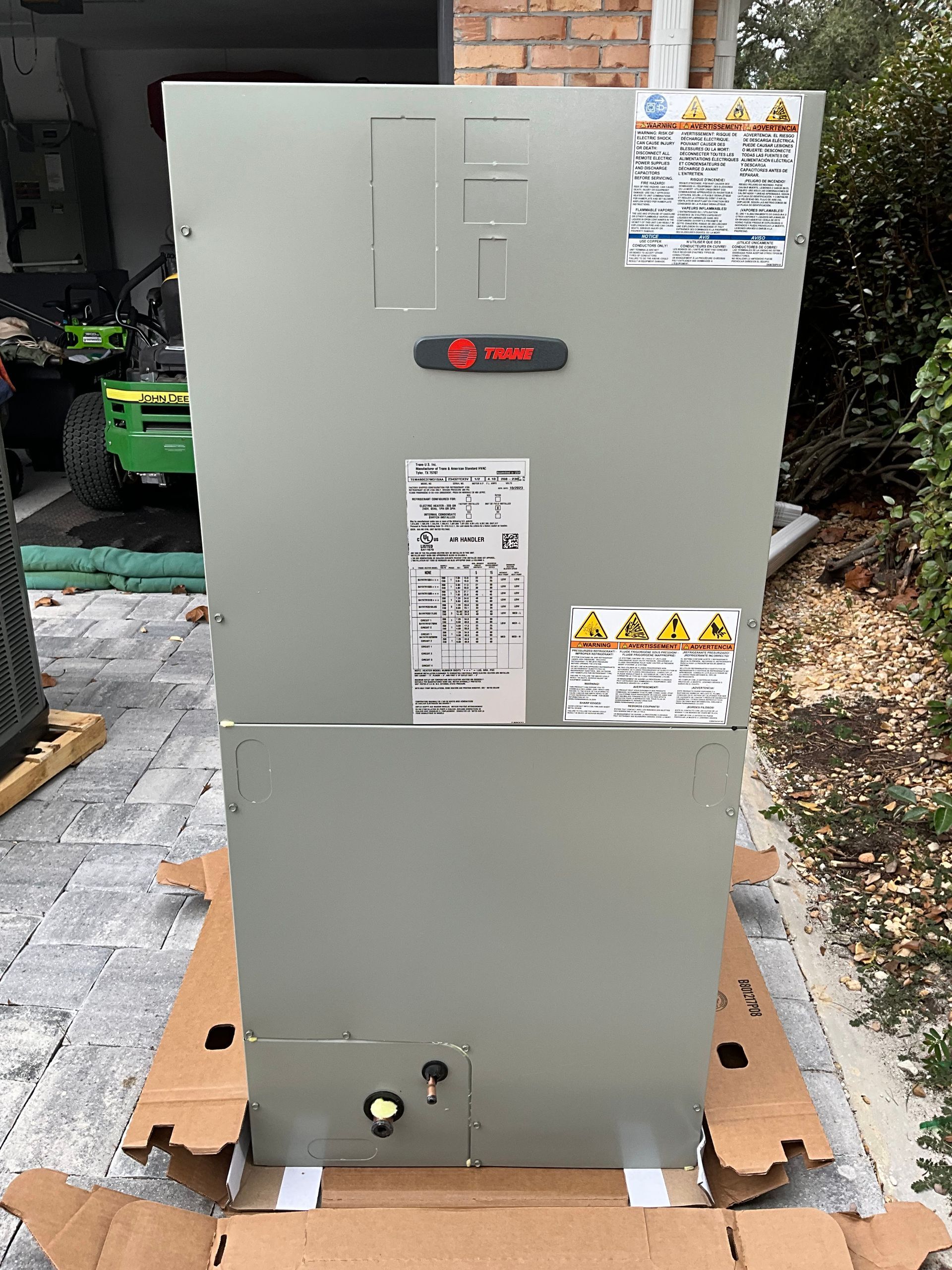 A large air conditioner is sitting on top of a cardboard box.