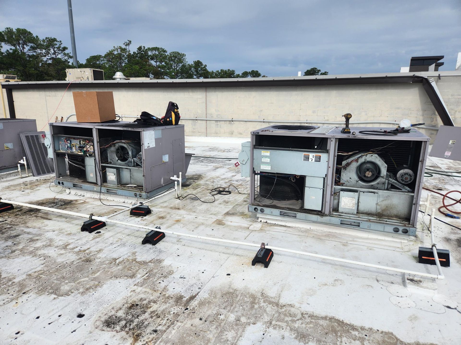 Two air conditioners are sitting on top of a roof.