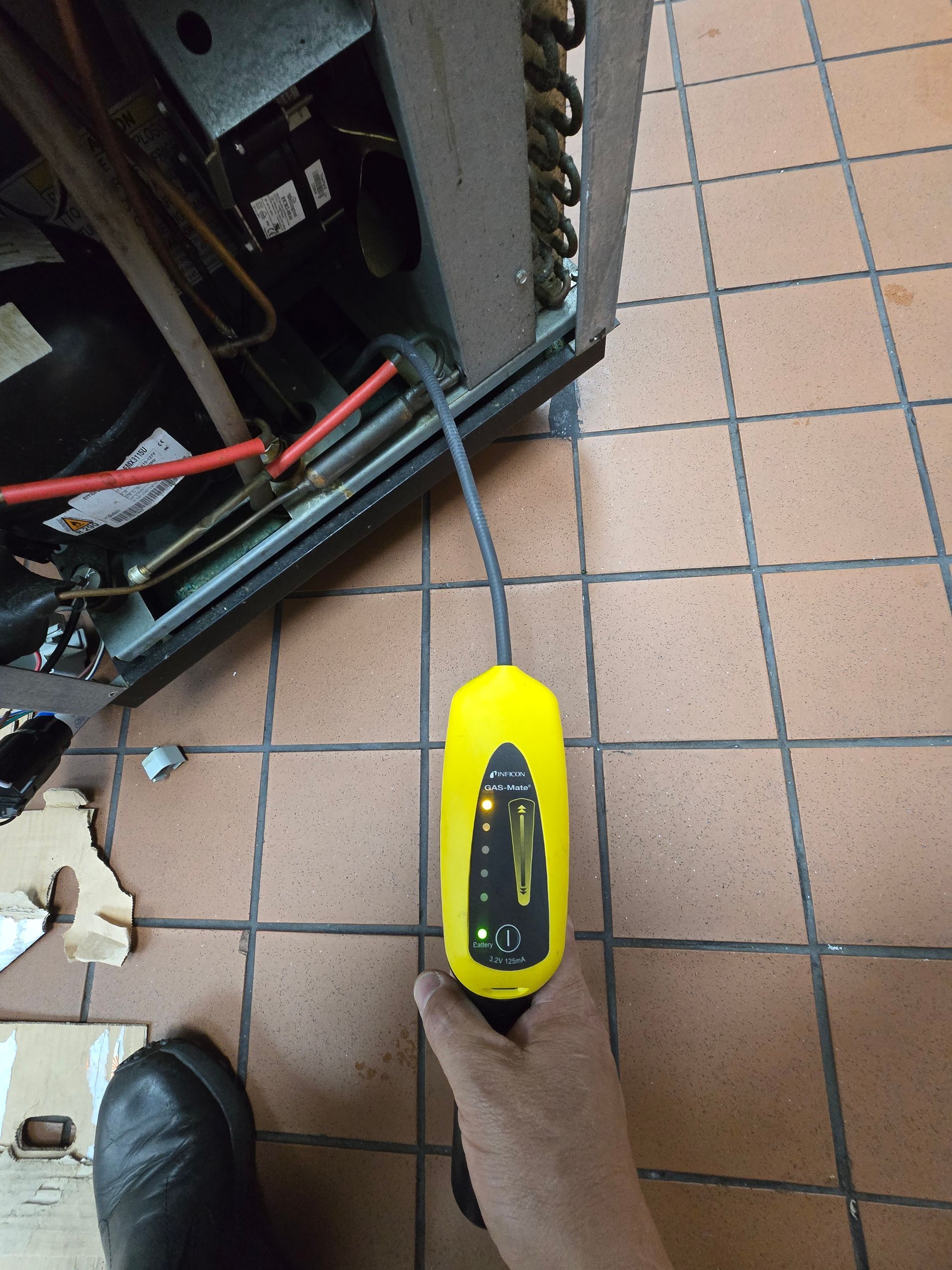 A person is holding a yellow screwdriver in front of a refrigerator