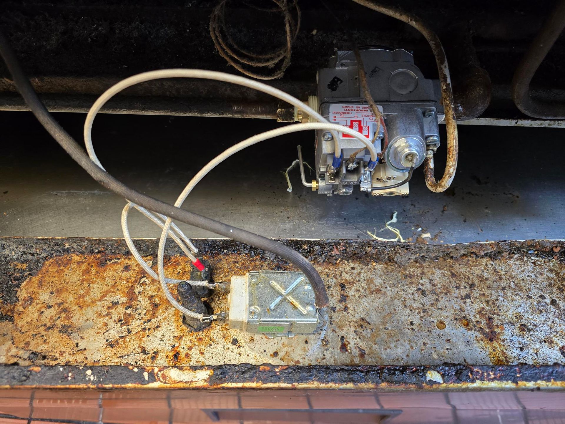 A close up of a rusty metal surface with wires coming out of it