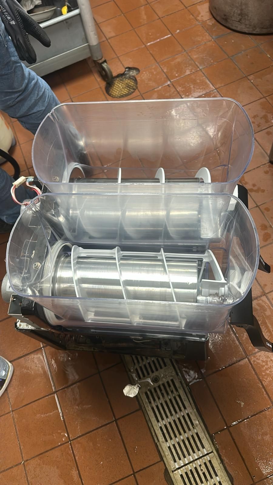 A machine is sitting on a tiled floor next to a drain.