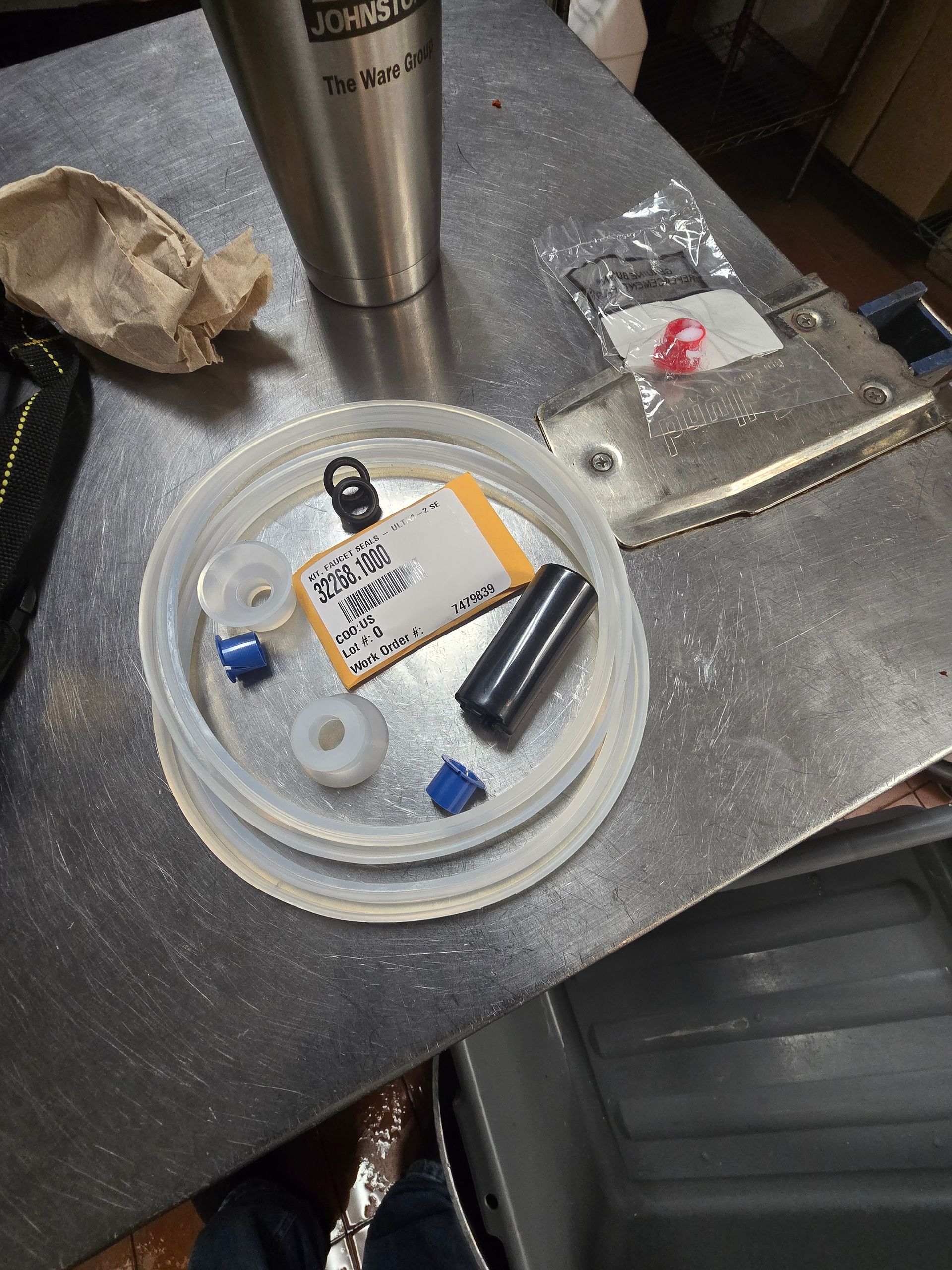 A stainless steel tumbler is sitting on a table next to a plastic lid.