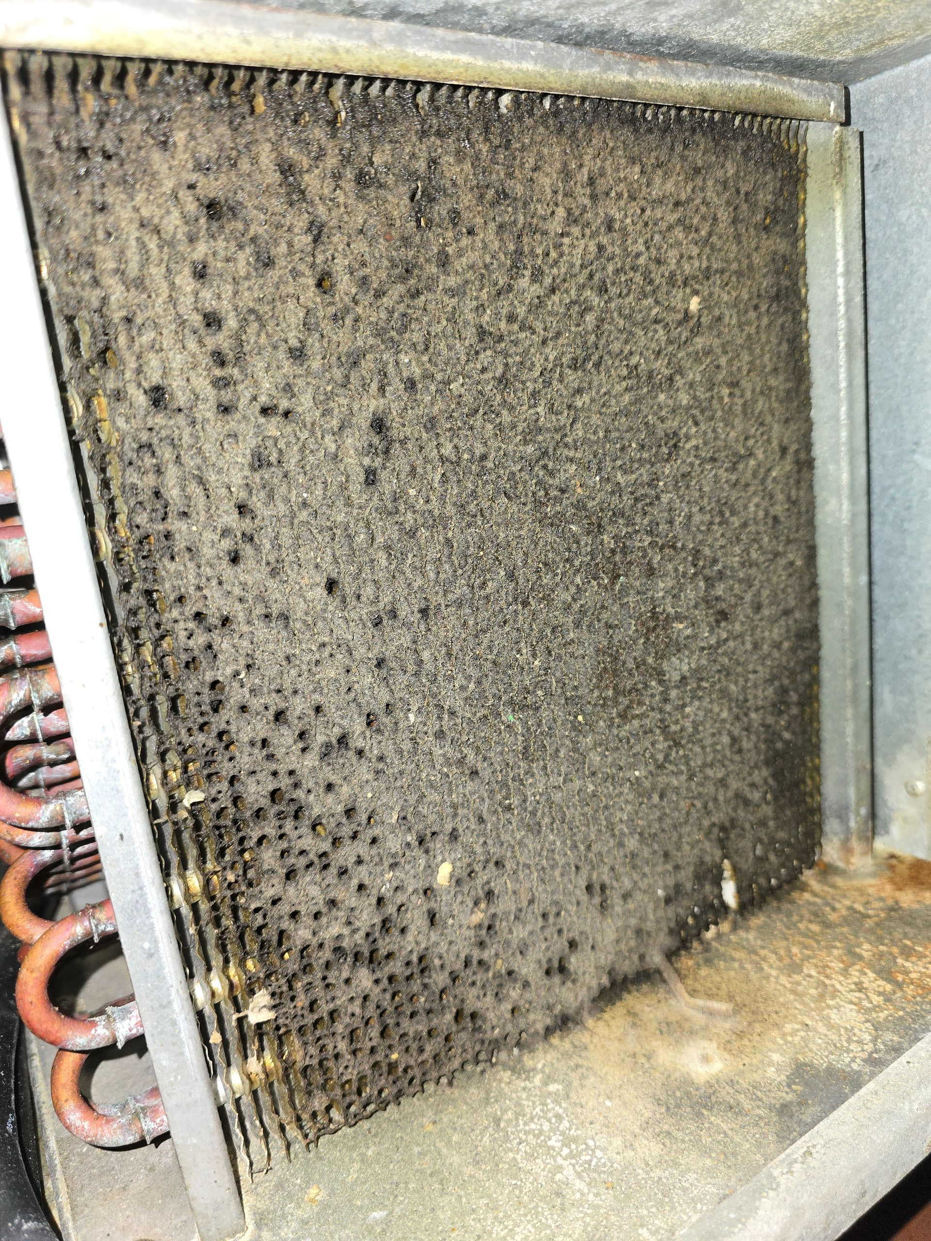 A close up of a dirty air conditioner coil with a lot of dust on it.