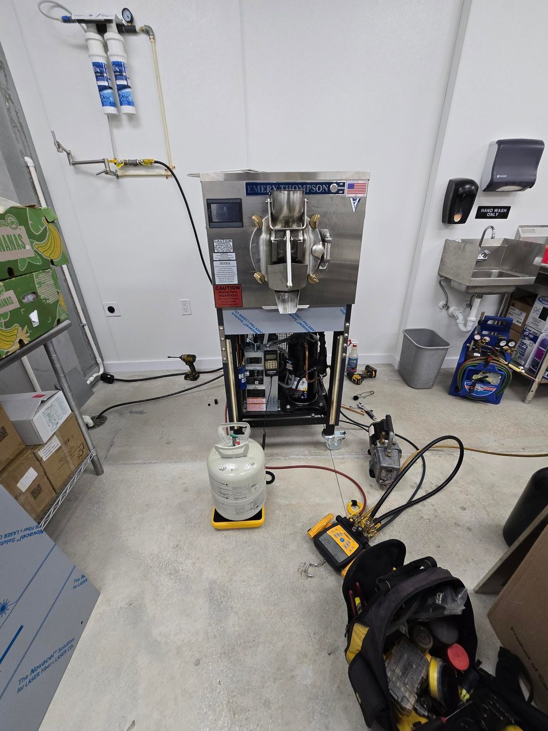 A machine is being repaired in a room with a propane tank on the floor.