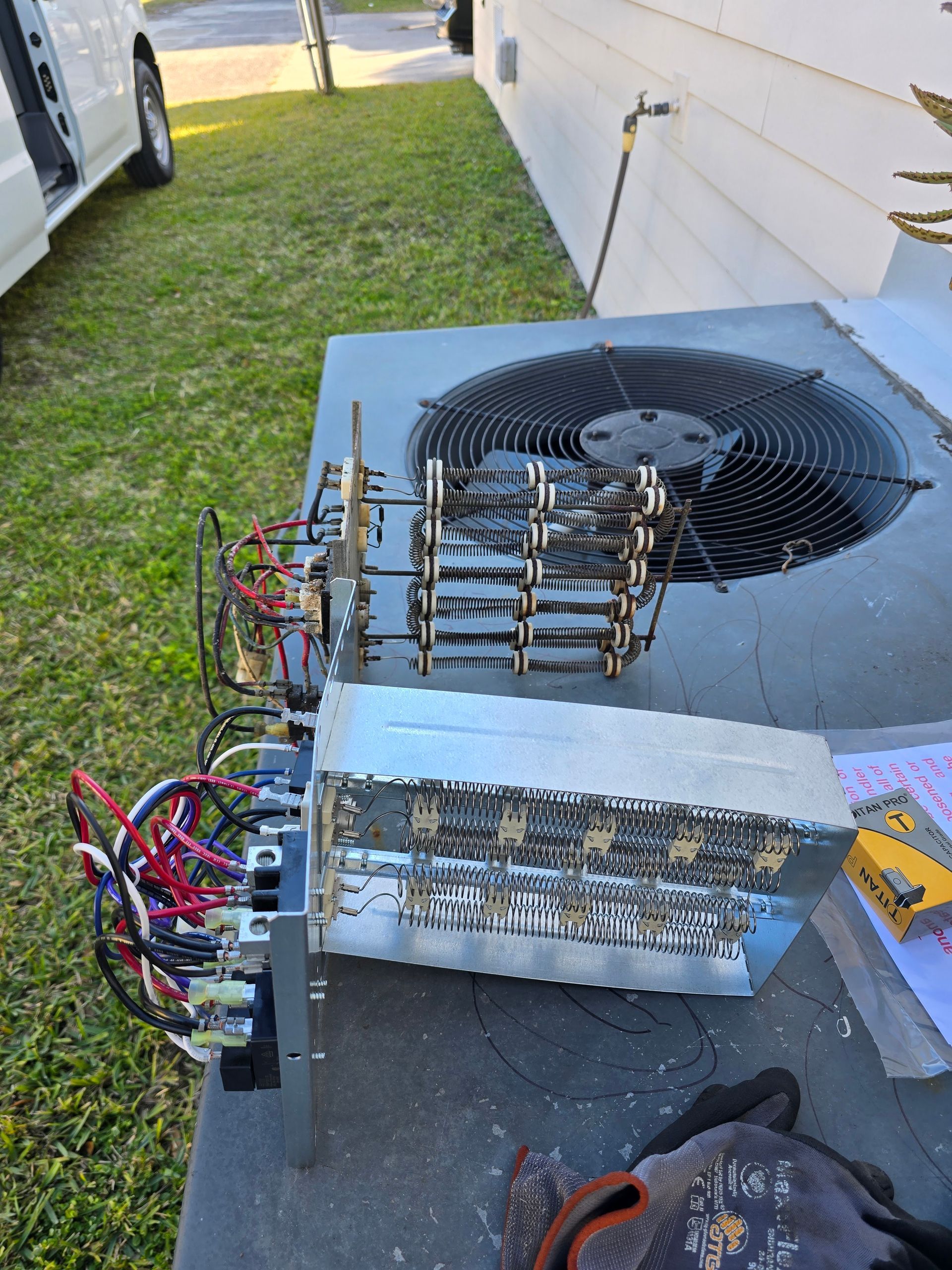 A person is working on an air conditioner outside of a house.
