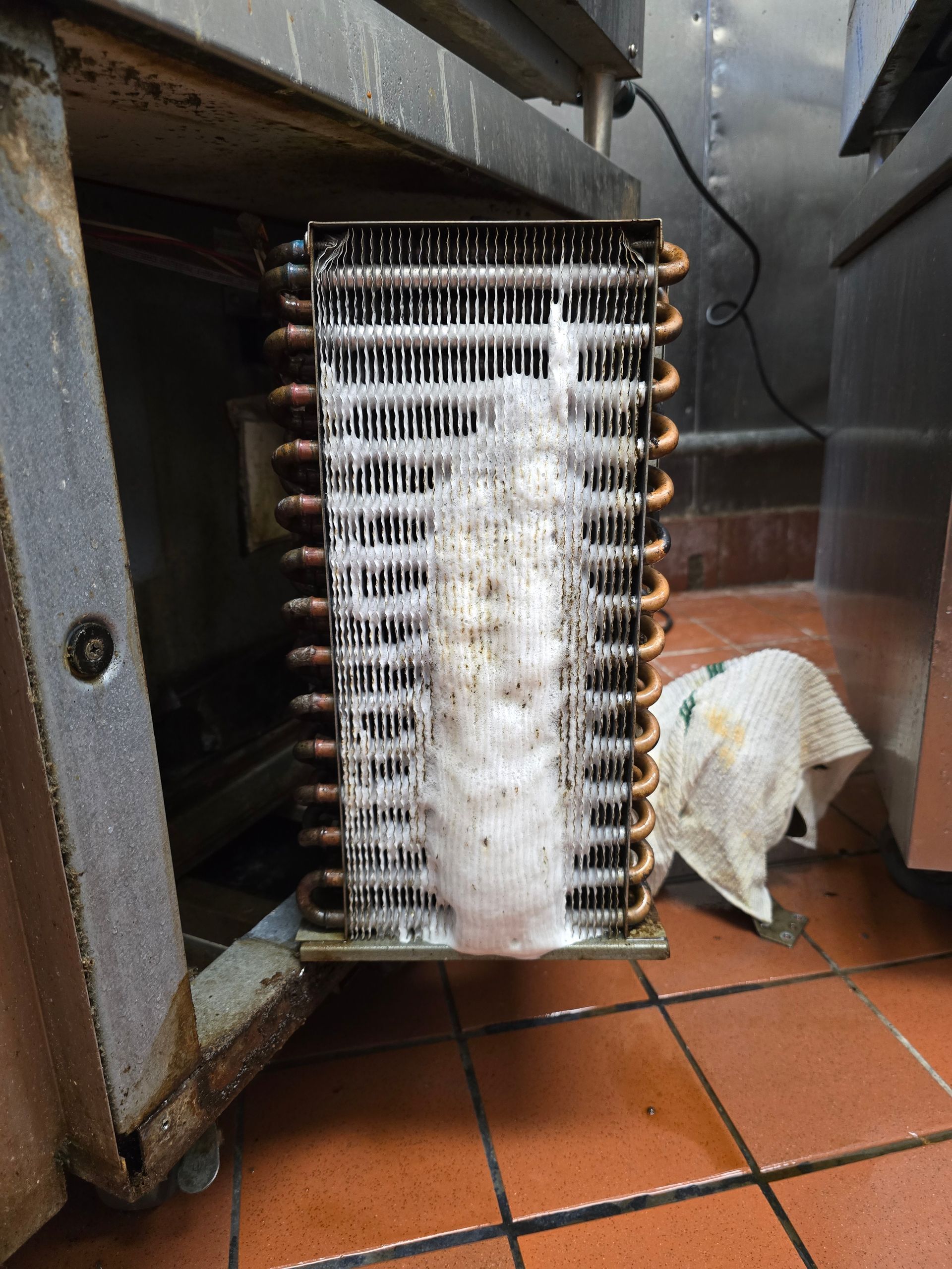 A refrigerator evaporator is sitting on a tiled floor