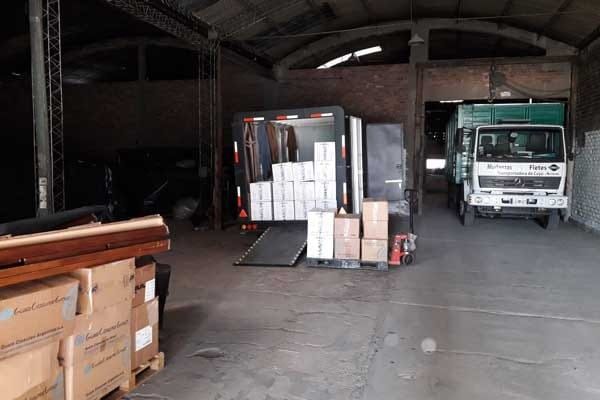 Camiones cargando y descargando cajas en un almacén.