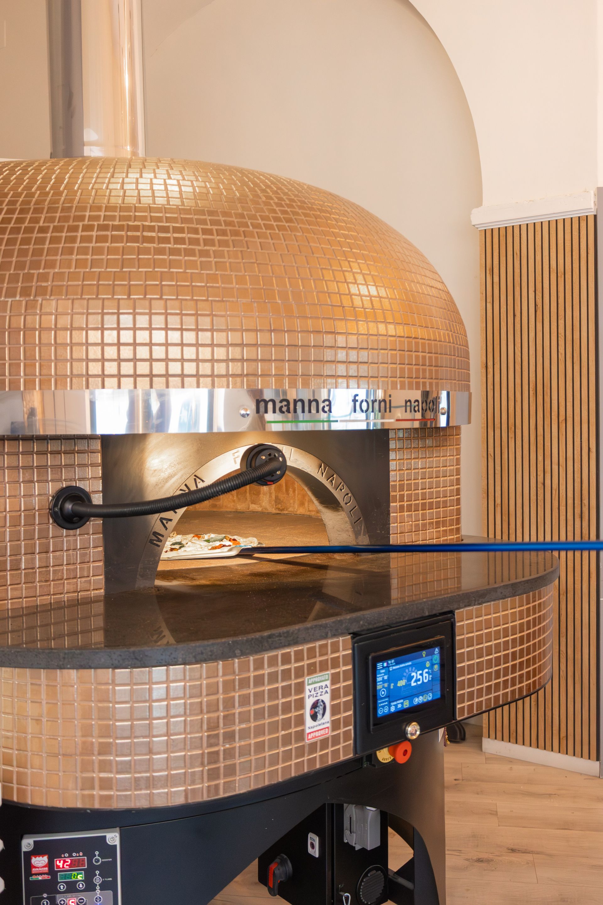 Forno per pizza con cupola in rame e pizza all'interno, nella cucina di un ristorante.
