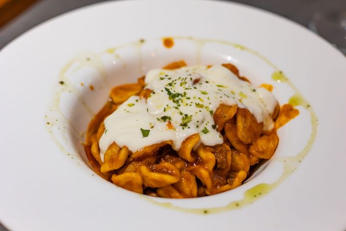 Pasta con cremosa salsa gialla, funghi e formaggio grattugiato su un piatto bianco