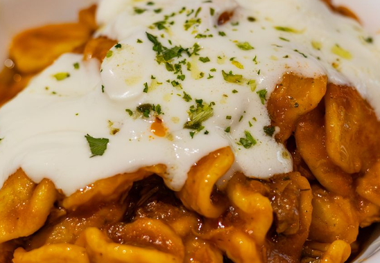 Primo piano di un piatto condito con una cremosa salsa bianca e cosparso di erbe aromatiche.