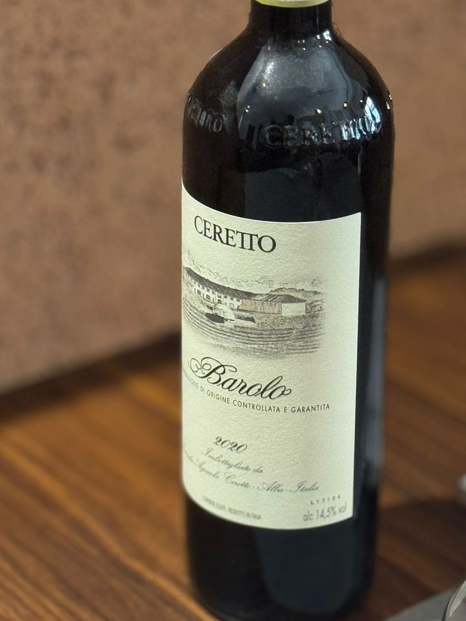 Ciotola di stufato di melanzane con basilico, guarnita con pomodorini e olive su un tavolo rustico.