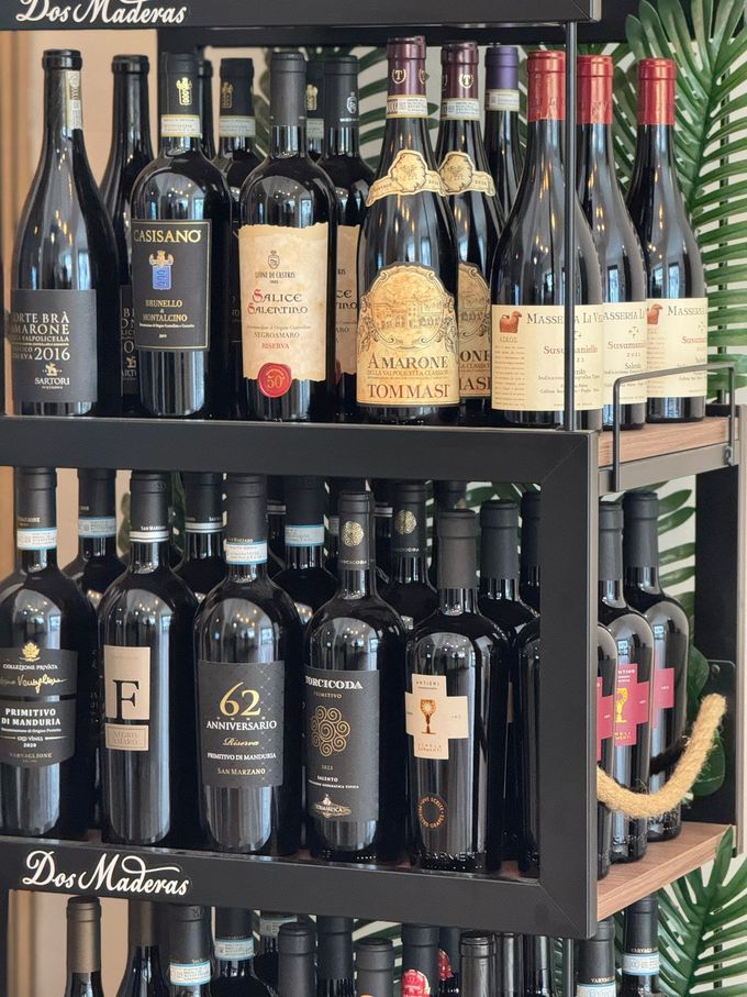 Antipasto servito su un piatto con guarnizione di pomodoro, accanto a un bicchiere di vino rosso e un bicchiere d'acqua.