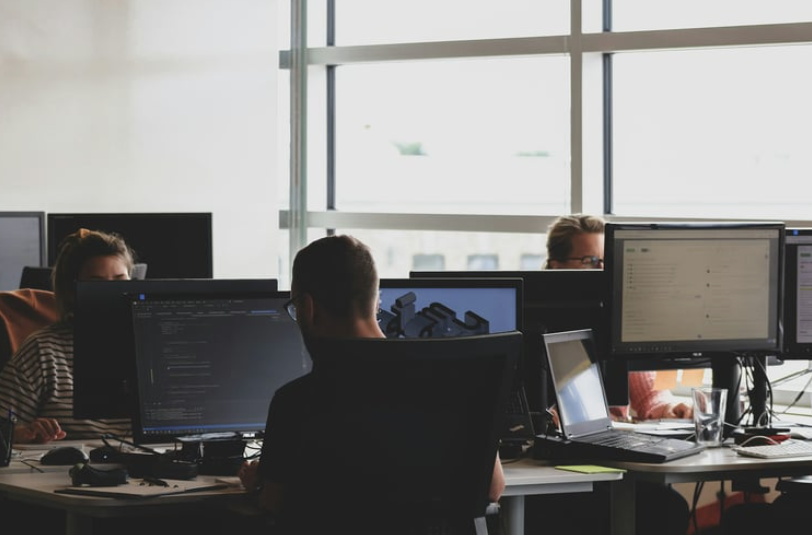 People working at desks with computers in a bright, modern office space.
