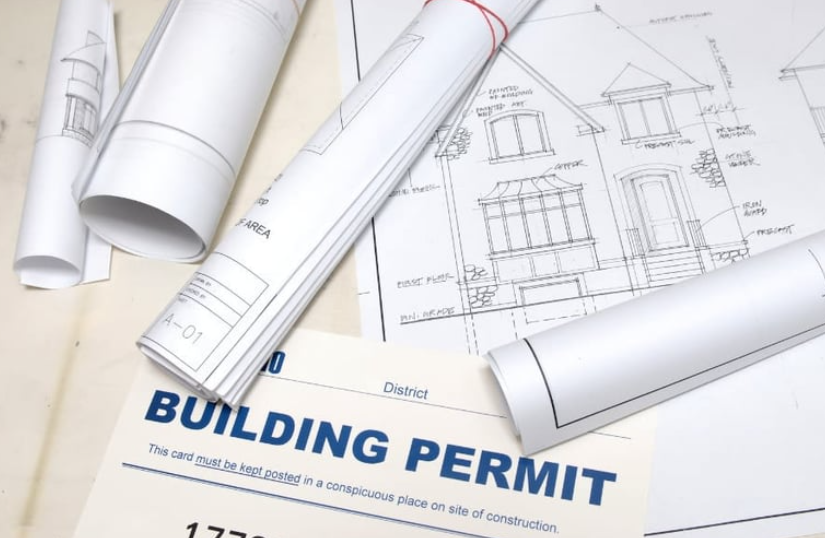 Blueprints for a house lying next to a building permit document.