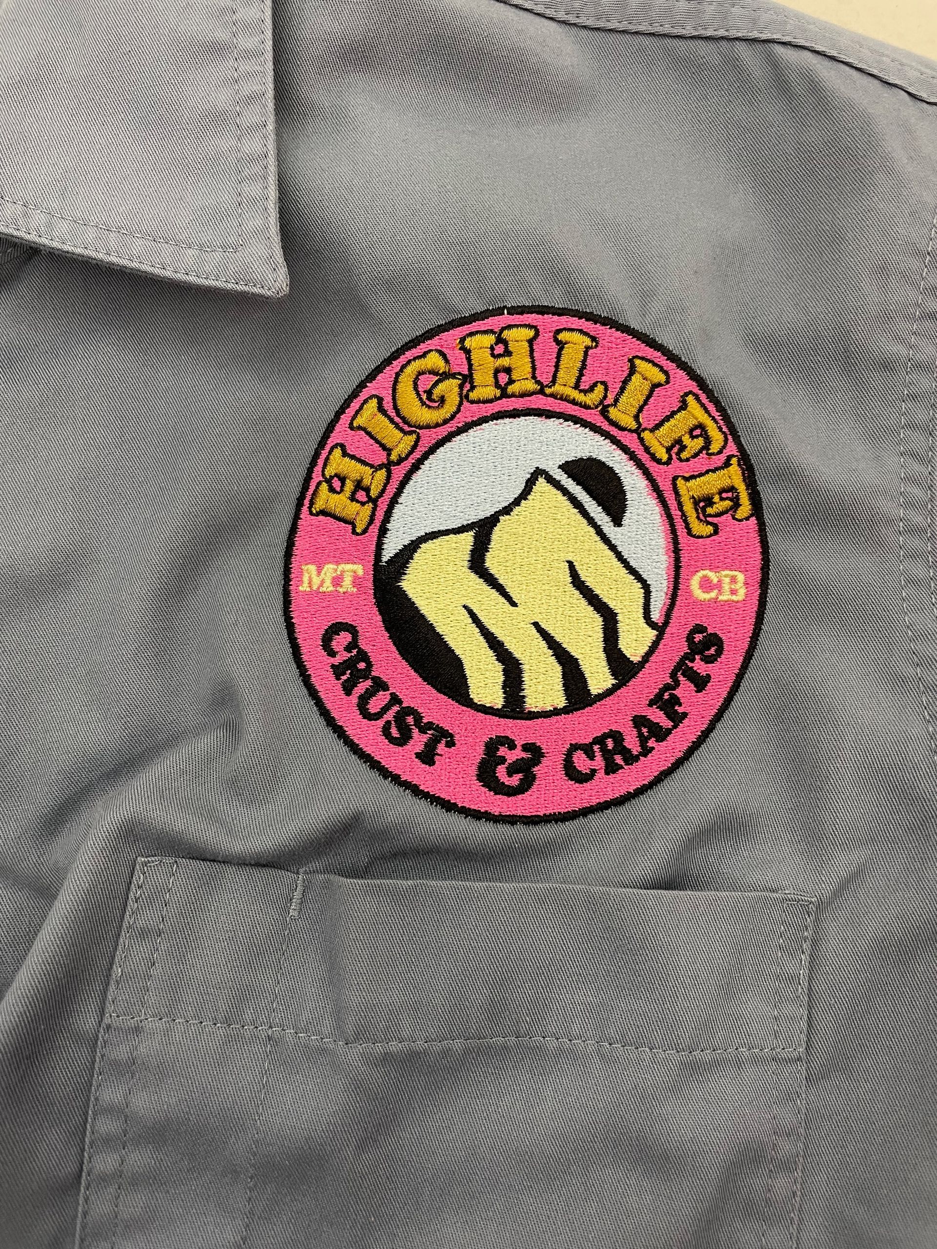 A close up of a high life crust & crafts logo on a shirt.