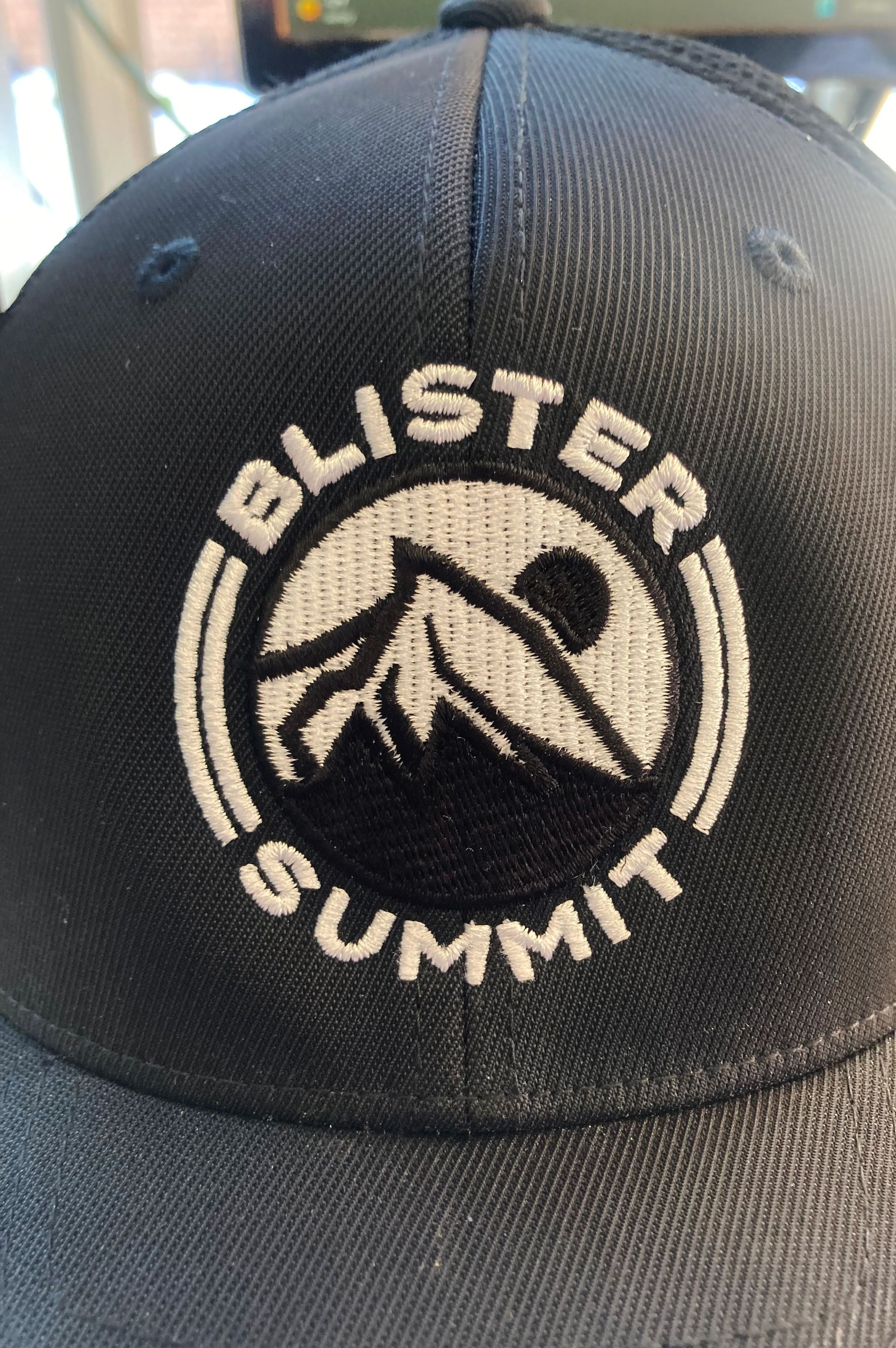 A close up of a baseball cap with the word blister summit embroidered on it
