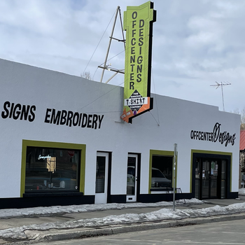 A white building with a sign that says signs embroidery