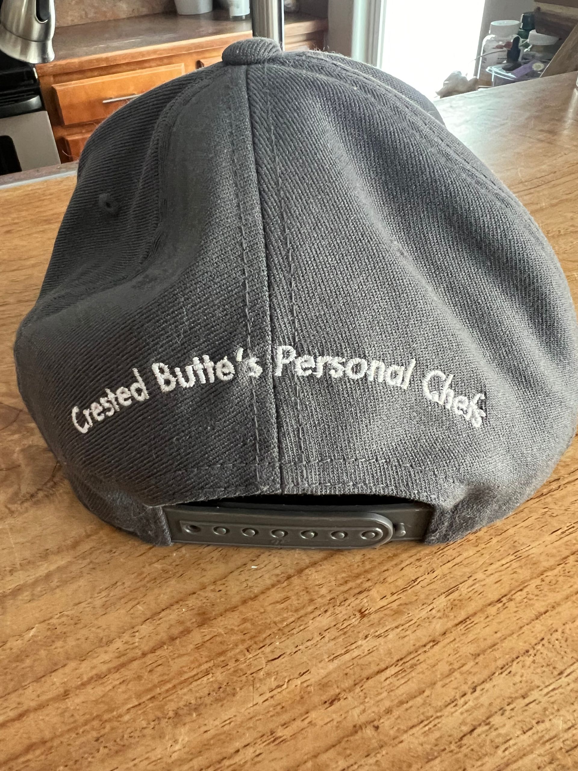 The back of a baseball cap is sitting on a wooden table.