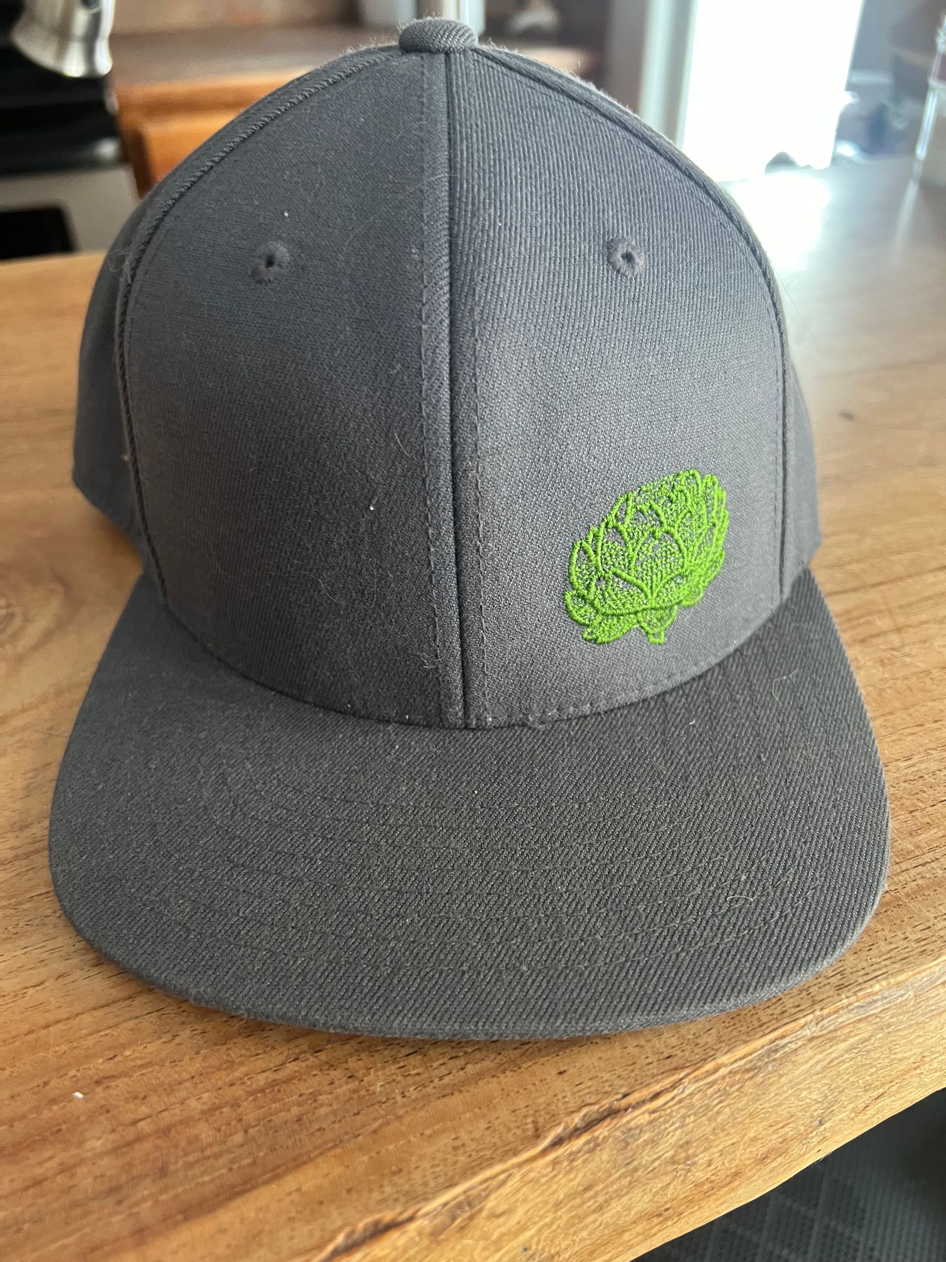 A gray baseball cap is sitting on top of a wooden table.