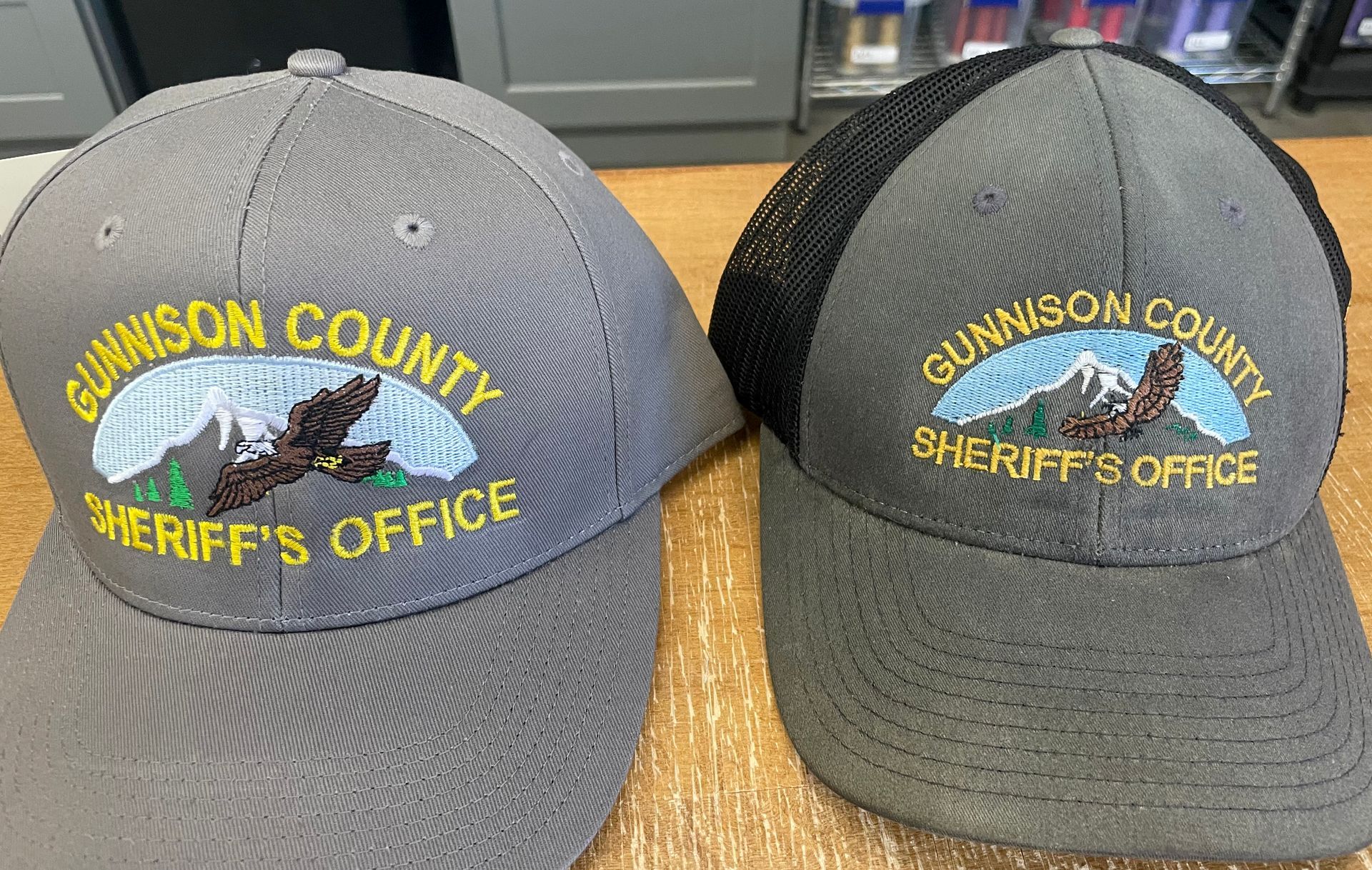 Two gunnson county sheriff 's office hats are sitting on a table.
