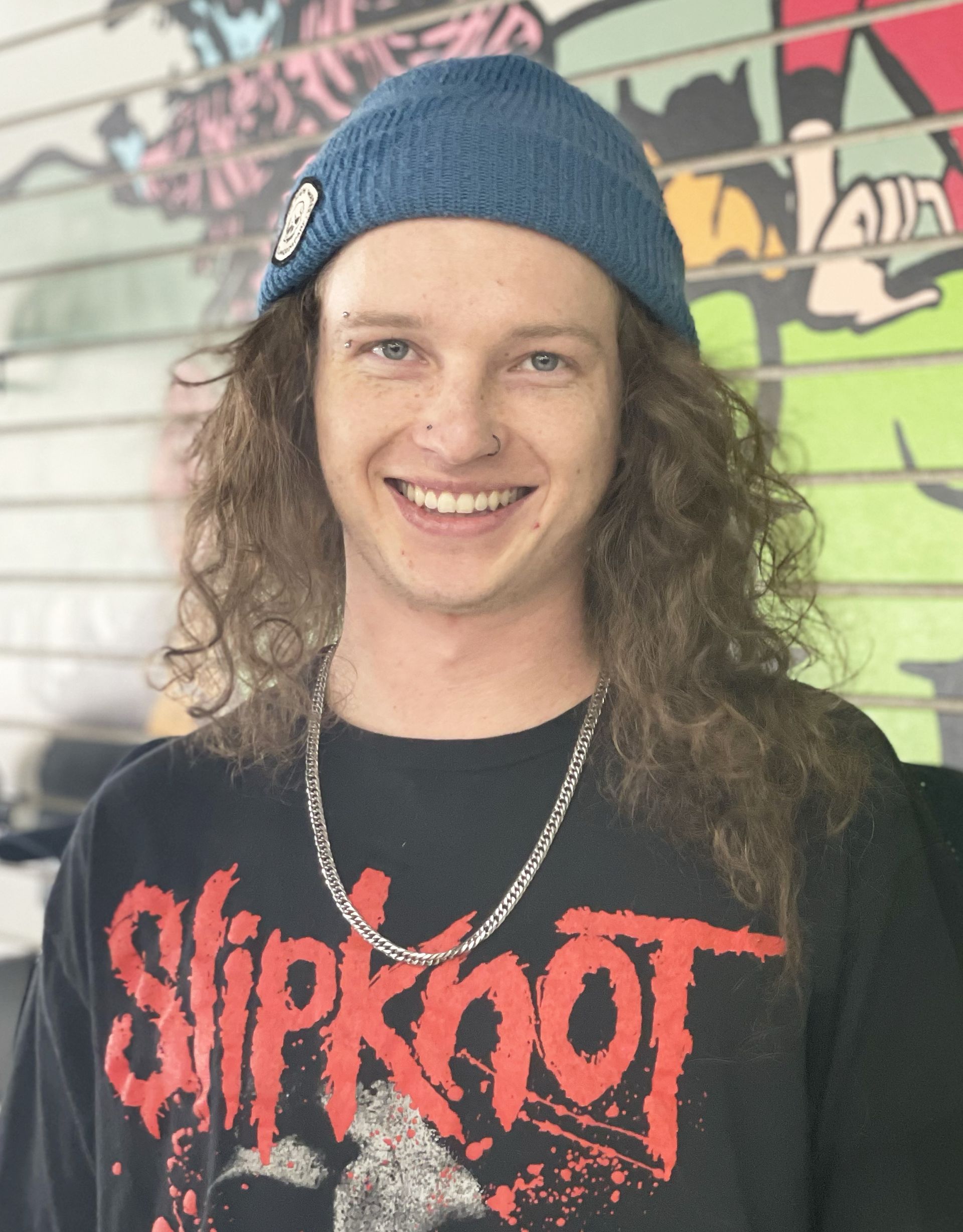 A young man wearing a slipknot shirt and a blue beanie