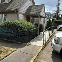 A car is parked in front of a house with a ramp leading to the front door.