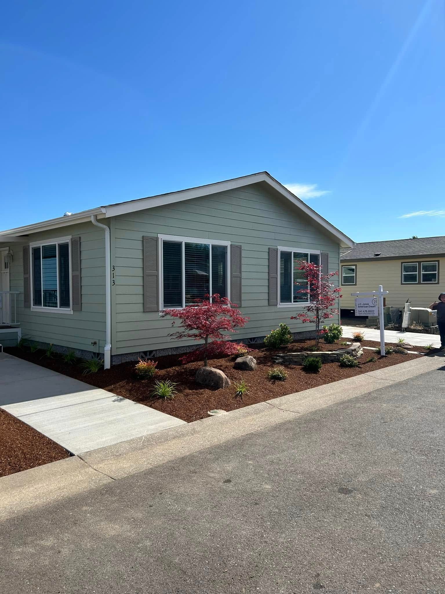 A mobile home with a lot of windows and a tree in front of it.