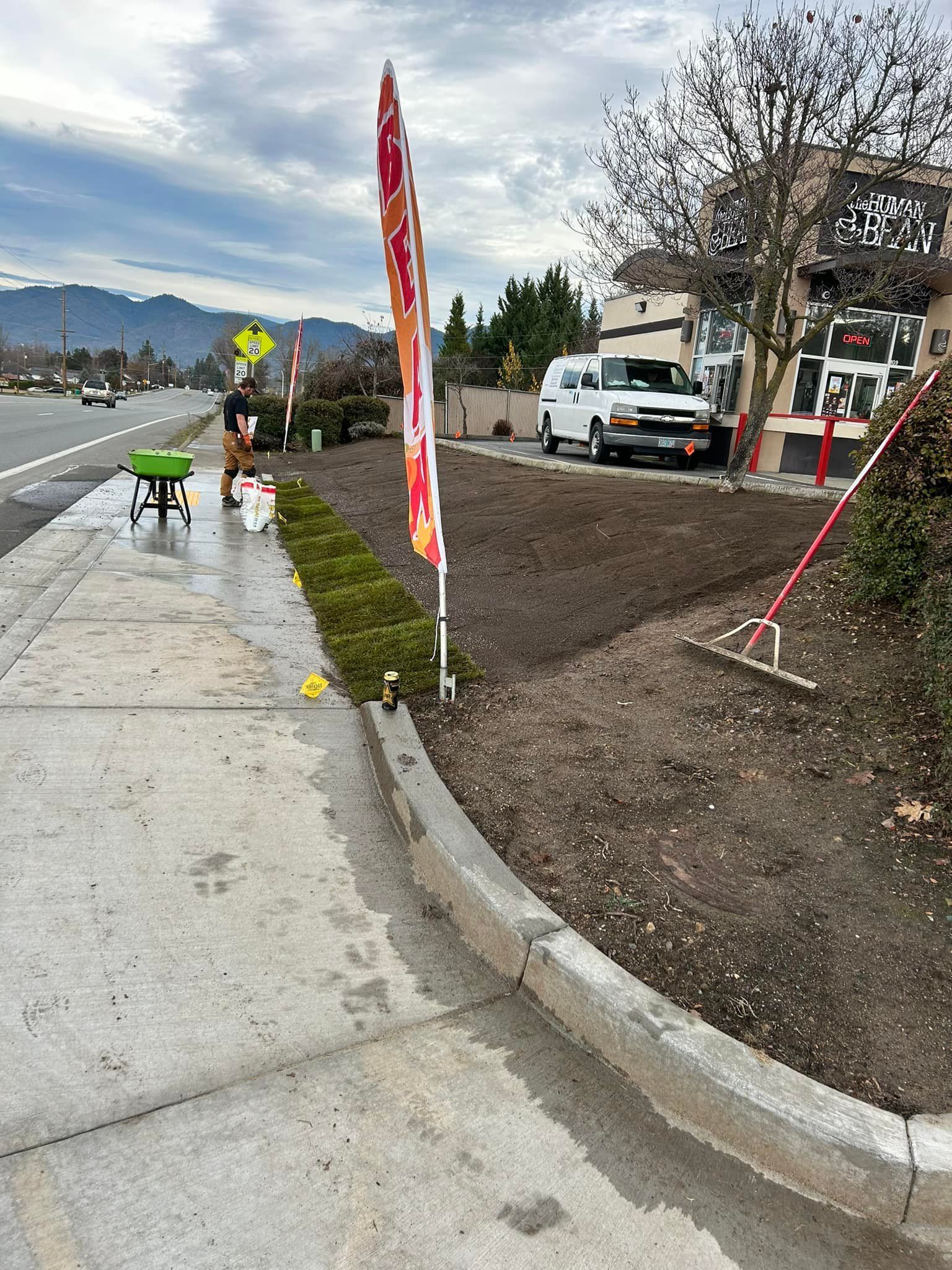 A man is standing on a sidewalk next to a road.