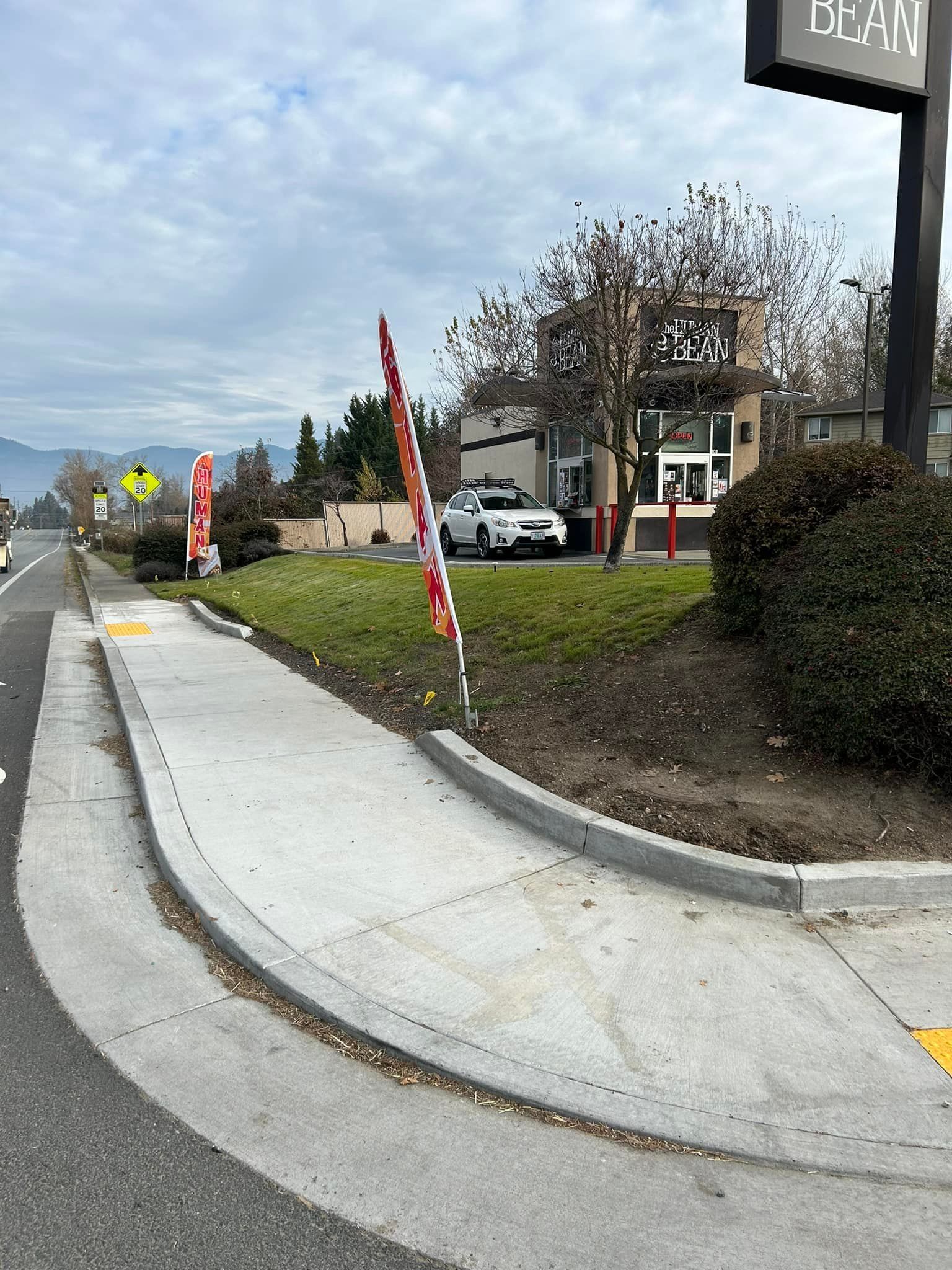 A sidewalk leading to a parking lot with a building in the background.